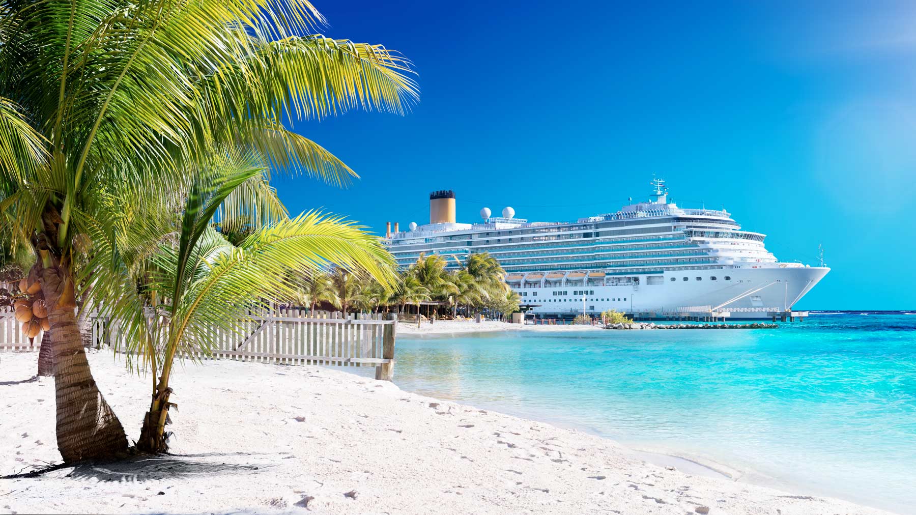 A cruise ship in a tropical destination with white sandy beaches, palm trees, and turquoise waters