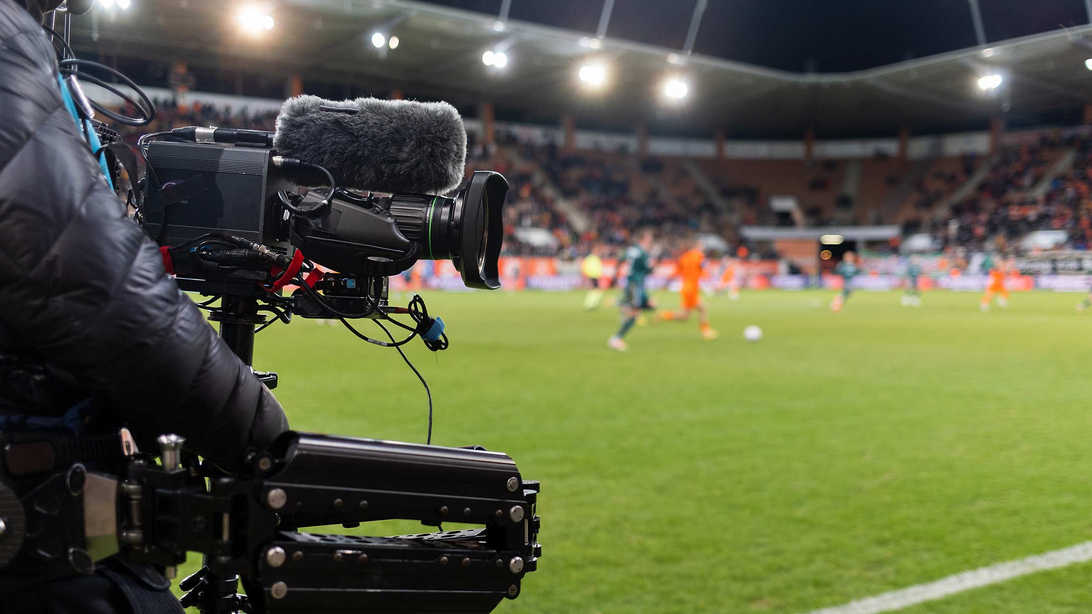 A broadcast camera filming a soccer game in a full stadium