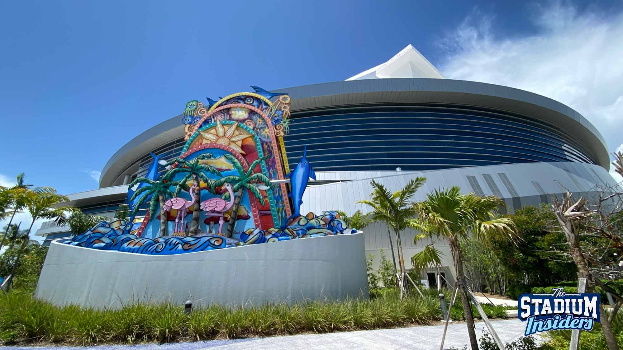 The facade of loanDepot park and its famous statue with flamingos, palm trees, and sunshine